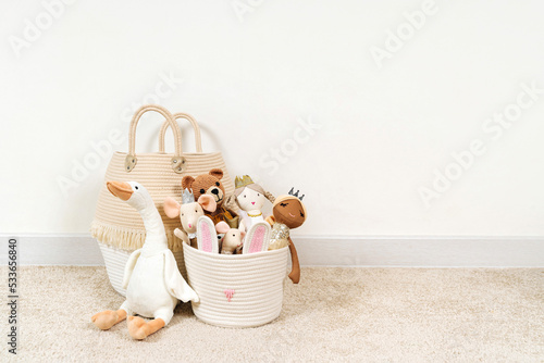 Beige Toy Storage Baskets in the children's room. Cloth stylish Baskets with toys and rag dolls. Organizing and Storage Ideas in nursery. Clean up toys and reduce the clutter. House cleaning.