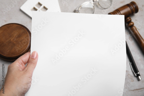 Woman holding last will and testament at light grey table, closeup