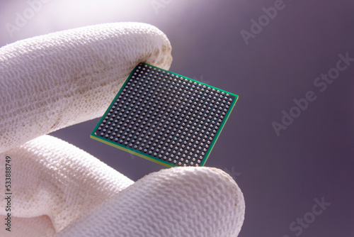 Semiconductor BGA chip in a hand on a gray background