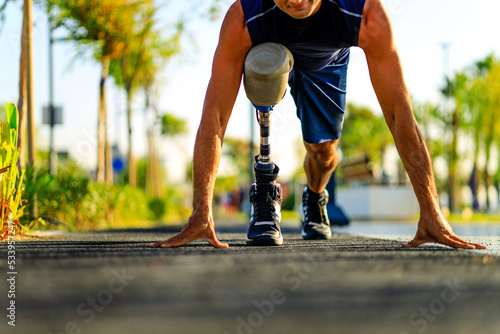 disabled athlete man with prosthetic leg starting to run at the beach on a treadmill outdoors at sunset