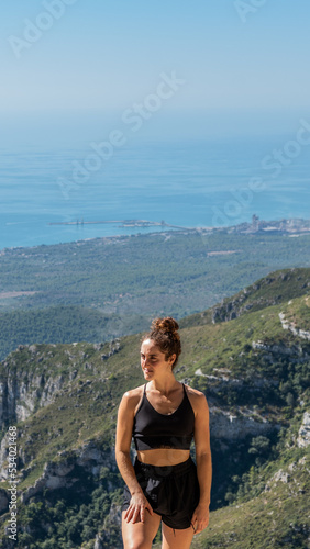 Caucasian blonde woman in front of a view in the mountain looking at the side
