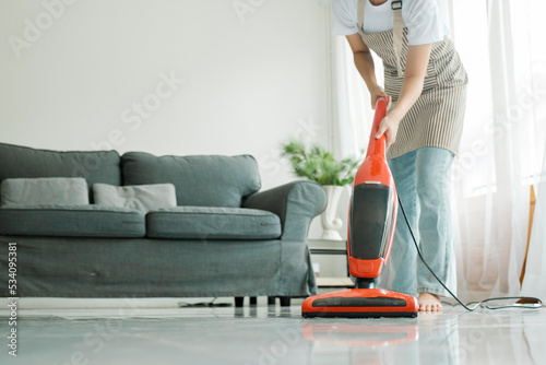 Young woman cleaning house with vacuum cleaner.