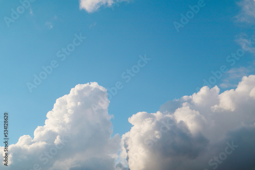 White, fluffy clouds in blue sky. Background from cumulus clouds. Scenery above the clouds