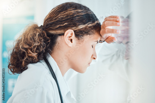 Sad, stress and burnout with doctor against window with headache from healthcare, medical or nurse. Mental health, depression and anxiety with woman working in hospital while tired, fear and fail