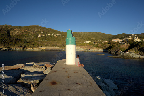 homme assis à côté d'un phare au coucher du soleil - Cap Corse