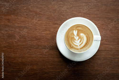 Cappuccino or latte with frothy foam, coffee cup top view on wooden background. Cafe and bar, barista art concept.