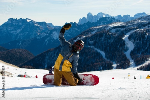 Snowboarder sitting on knees and waving at the camera