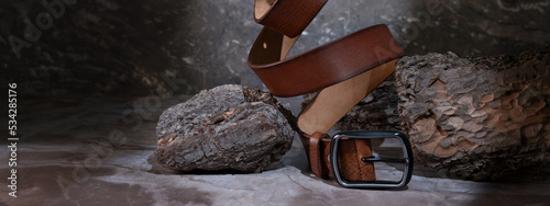 leather belt on a dark background with bark and natural stone on the background. levitation. stylish details of men's clothing.