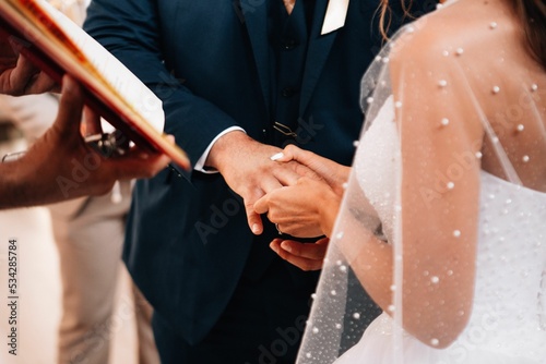 Closeup shot of the bride putting on the groom's wedding finger in the church