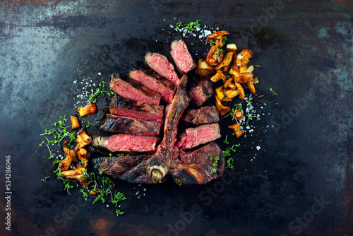 Traditional barbecue dry aged wagyu porterhouse beef steak bistecca alla Fiorentina with chanterelles and onion rings sliced and served as top view on an old rustic board with copy space
