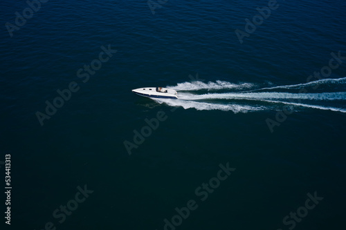 Luxurious Blue boat motorboat rushes through the waves of the blue Sea. Boat fast moving aerial view. Luxurious boat fast movement on dark water.