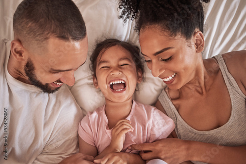 Children, family and bedroom with a girl, mother and father laughing, joking or tickling in bed from above. Kids, happy and love with a woman, man and daughter having fun together in their home