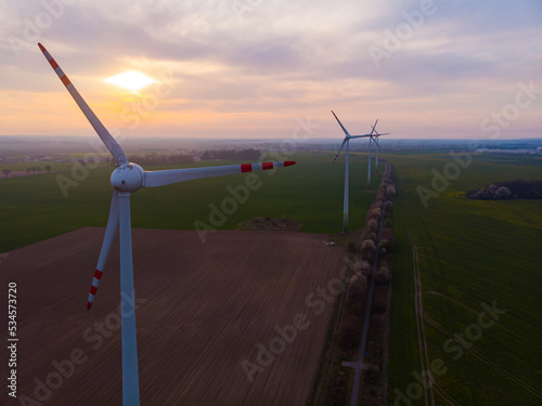 drone photography of the sunset over a wind farm with a view of the sea and a peninsula in the background; green energy