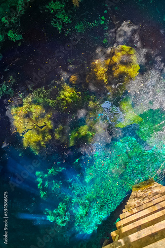 Blue turquoise water limestone cave sinkhole cenote Tajma ha Mexico.