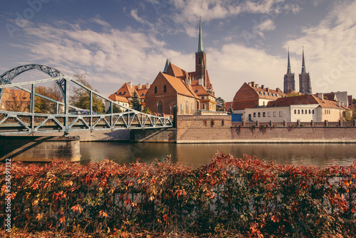 View of medieval town: Tumski Bridge between the islands of Wyspa Piasek and Ostrow Tumski and Roman Catholic Church of St. NMP in autumn. Poland, Wroclaw.