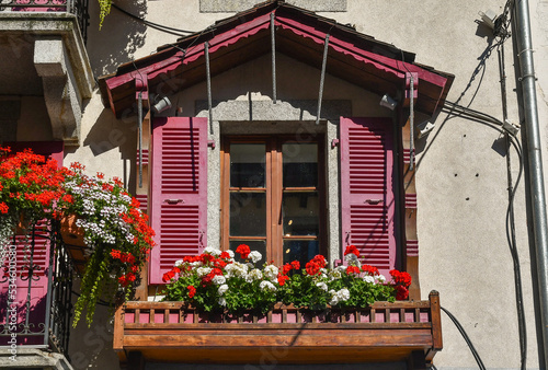 Detail of the window of a typical alpine house with flowering geraniums on the sill in summer, Chamonix-Mont-Blanc, Haute Savoie, France