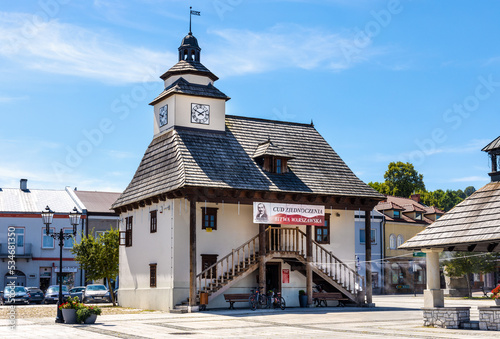 Historic Town Hall Ratusz Miejski and renewed wooden well at Rynek Main Market square in old town quarter of Pilica in Silesia region of Poland