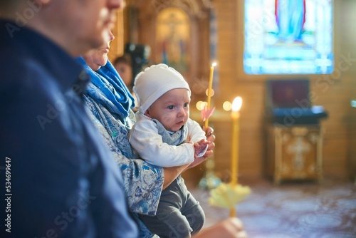 A small child at a baby christening ceremony in a church. the godfather holds a little boy in his arms. Baptism of a newborn. The sacrament of baptism. Child and God