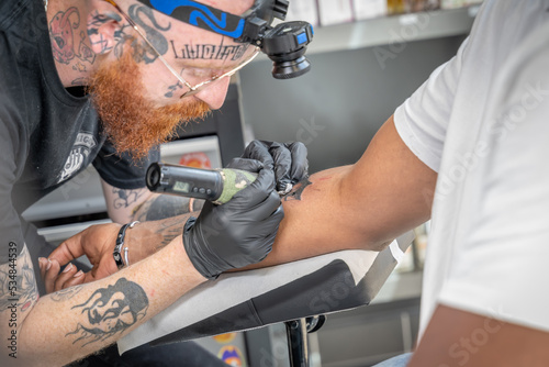 tatoueur en train de réaliser un tatouage flash avec une aiguille électrique
