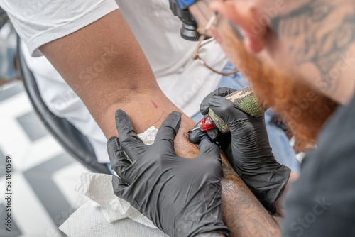 Tatoueur en train de tracer un tatouage sur un avant bras