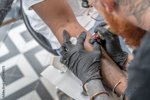 Tatoueur en train de faire un tatouage sur un avant bras