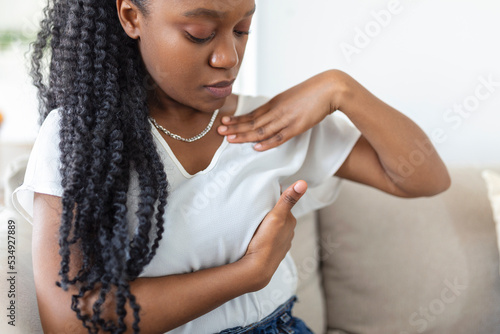 Young African American woman palpating her breast by herself that she concern about breast cancer. Healthcare and breast cancer concept