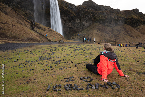 Mujer joven observando la cascada de Seljalandsfoss, en Islandia.