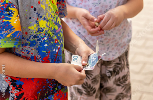 Two anonymous children holding Polish money, bills, banknotes and coins in hands closeup, detail. Kids receiving pocket money, monthly allowance simple concept, business, family finance management