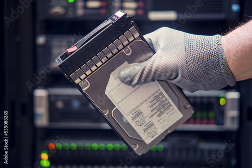 A hard disk for a raid in the hands of a man at a data storage server, close-up
