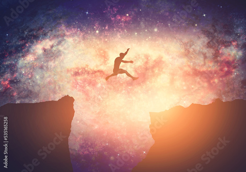 Making a dream come true. Man jumping between mountains on galaxy night sky