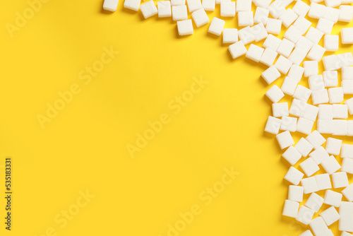 White sugar cubes on yellow background, flat lay. Space for text