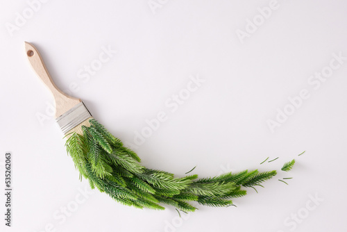 Creative winter concept with Christmas tree branches and paint brush on white background. Nature composition, flat lay, copy space. Minimal New Year concept.