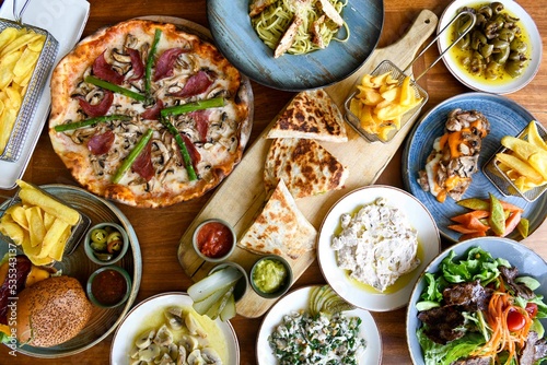 Traditional Turkish cuisine. Pizza, pita, pidesi, sucuk, hummus, kebab. Many dishes on the table. Serving dishes in restaurant. Background image. Top view, flat lay