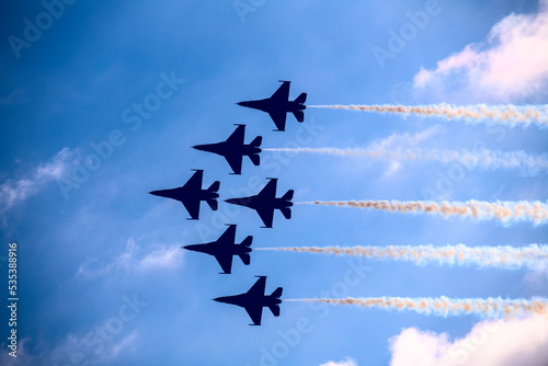 Fighter jets in formation flying past clouds