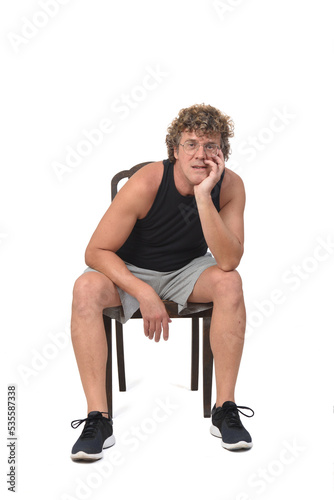 front view of a man with sportswear sitting on chair hand on face on white background