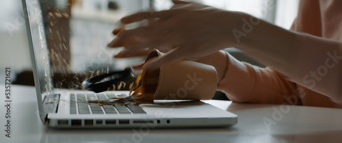 CU Caucasian female working from home, spills coffee on keyboard of her laptop