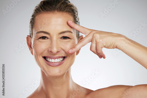 Skincare, beauty and face of mature woman with anti aging product to reduce lines and wrinkles against grey mockup studio background. Portrait of happy model showing care for skin with cosmetology