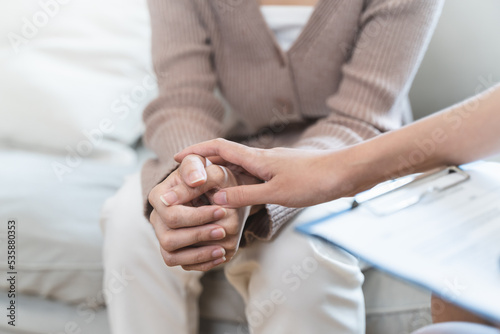 psychologist touching hands and encouraging stressed woman have by about mental health problem