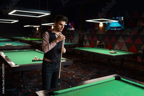 Portrait of young man preparing billiards cue