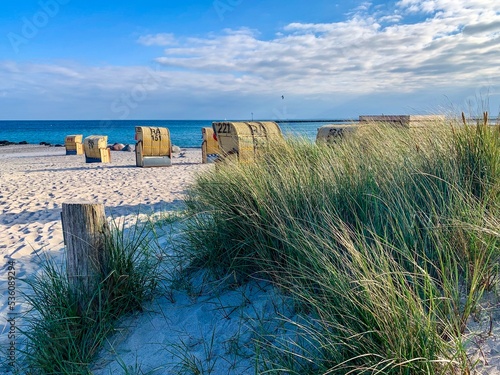 View of the sandy beach, traditional north german beach chairs and beach grass on the island Fehmarn on Baltic sea