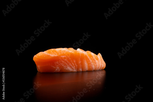 japanese food an isolated piece of salmon sashimi in close up macro photo on black background from standing angle
