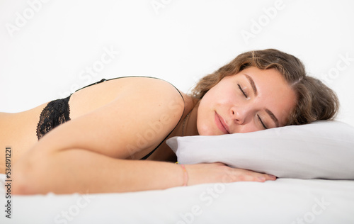 Portrait of seminude young brunette sleeping calmly in cozy white bed