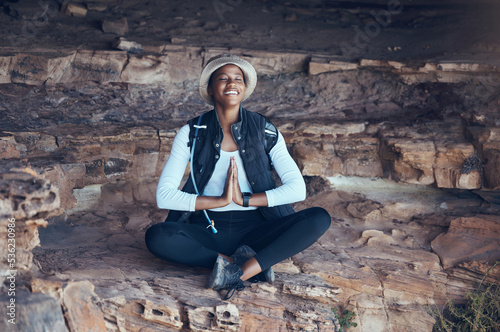 Nature, yoga and black woman in buddhist meditation cave in Thailand, zen, nature and wellness exercise. Earth, fitness and mountain worship by happy, calm and meditating lady in yoga pose for peace