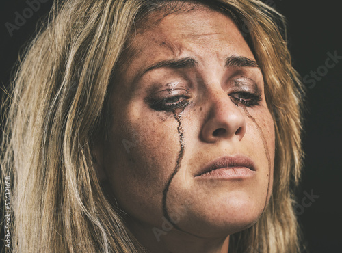 Sad, depression and woman crying with makeup smudge on face from tears with studio wall closeup. Depressed, hopeless and unhappy girl with mental health problem in distress with messy mascara.