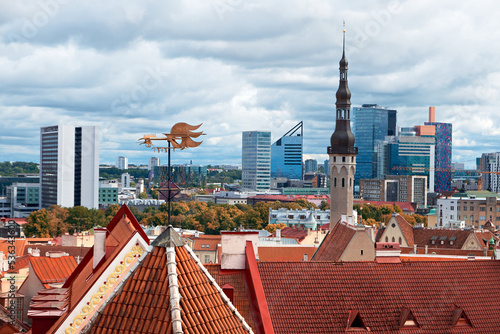 Bird view of historic city center of Tallinn, Estonia and modern town behind. Autumn trees, towers and orange tile roofs of ancient, medieval houses under cloudy overcast Northern sky with clouds.