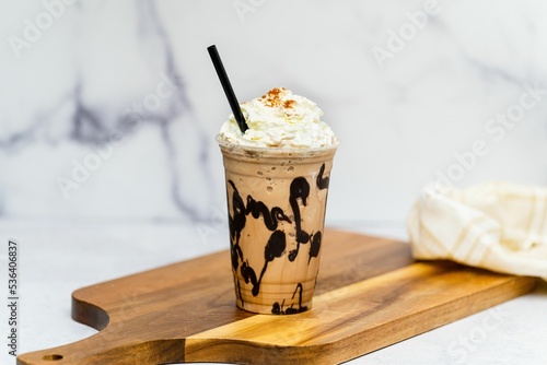 Tasty fresh Frappuccino with cream served on the wooden board