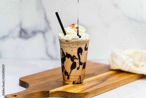 Tasty fresh Frappuccino with cream served on the wooden board