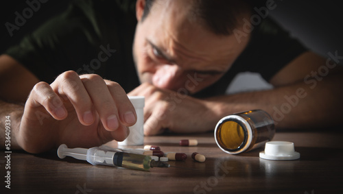 Drug addict man with a syringe and drugs. Addiction