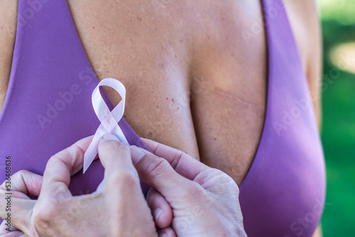 Breast Cancer Awareness Day. Anonymous woman attaches a symbol of Awareness and the fight against breast cancer to the clothes of another unrecognizable woman. Breast Cancer Awareness Day concept.Sign
