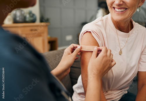 Woman, smile and plaster after injection for vaccine against covid. Happy, senior and lady vaccination for coronavirus on sofa in doctor office for health, wellness and safety from global pandemic